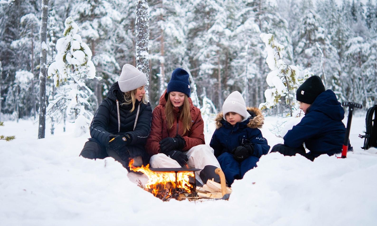 Family gathered around fireplace in winter forest in Dalarna